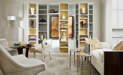 White living room with custom built-in shelving focal point displaying stacked books, pottery, and art pieces.