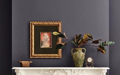 A white mantel with a decorative vase, framed artwork, a clock, and a small basket against walls painted Sherwin-Williams Midnight.
