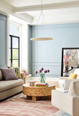 Sherwin-Williams Dutch Tile Blue–painted living room with a sofa and armchairs, round wooden coffee table, French doors painted dark purple using the color Mountain Fig, a White Snow ceiling and trim, and a large abstract art piece leaning against the back wall.
