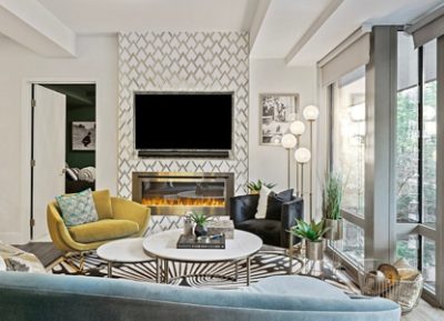 Stylish living room with TV, electric fireplace, and modern furniture featuring a geometric patterned accent wall, surrounding walls painted Sherwin-Williams Pure White, and large windows. 
