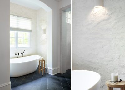 Modern bathroom with a freestanding bathtub, textured walls painted Sherwin-Williams Cotton, and stone tiles.