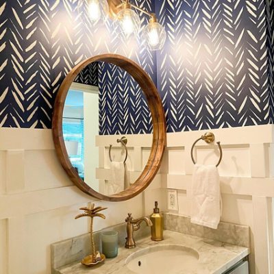 A small bathroom wall and vanity with blue and white, patterned wallpaper