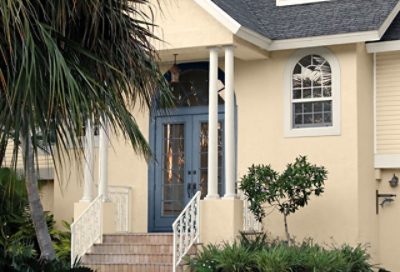 A cream beach house with white trim and a blue double entry door. S-W colors featured: SW 7678, SW 6385, SW 6243.