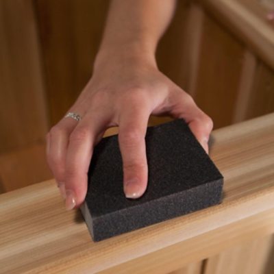 A woman sanding a bench to be painted