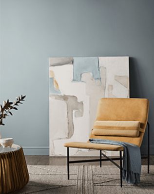 Blue walls with neutral chair and coffee table on textured rug.