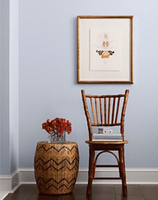 Light blue walls with print, wooden chair, and side table,.
