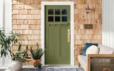 A front door painted olive green with cedar shake siding around it.