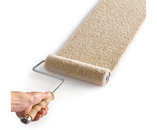 A person holding a paint roller with carpet being rolled out.