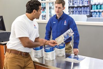 Un empleado de Sherwin-Williams ayudando a un pintor profesional en la tienda.