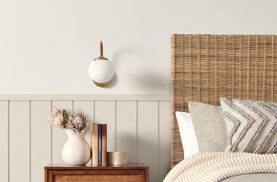 A bedroom painted Heron Plume SW 6070, paired with a bed and throw pillows, a wooden mesh headboard, and a small wooden nightstand.