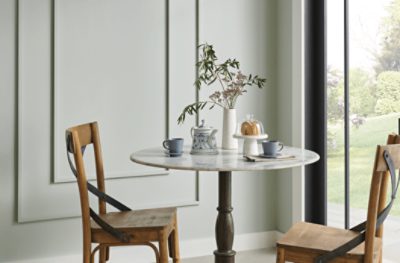 A breakfast nook painted Silver Strand SW 7057 with a circular table, two wooden chairs and French doors.
