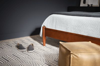 A bedroom with a geometric rug and SW 7076 Cyberspace painted walls.