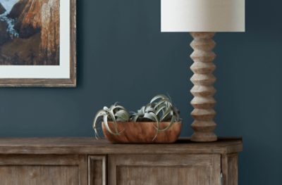 Walls painted Mount Etna SW 7625, paired with a painting on the wall, a wooden table and decorative lamp.
