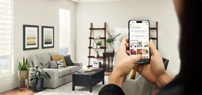 Une personne debout dans son salon utilisant un iPhone avec le Sherwin-Williams Color Expert Application.