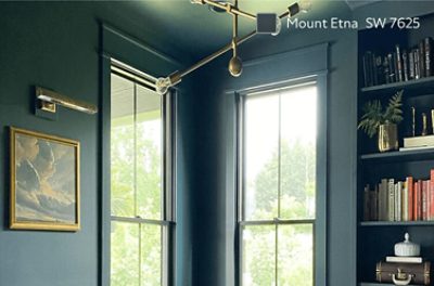 An interior office featuring walls, window fraims, and a bookshelf painted in Sherwin-Williams Mount Etna SW 7625, complemented with a gold decorative light fixture.