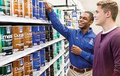 A Sherwin-Williams store associate helping a customer choose paint.