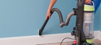 A person is using a vacuum to clean dust off a wall.