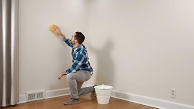 A man cleaning a wall with a sponge