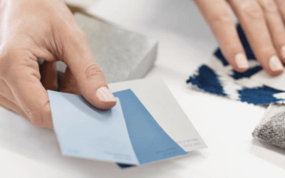 Hands holding three Sherwin-Williams color chips next to textiles of different patterns.