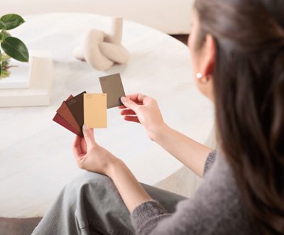 A person holding 4 small color chips in one hand and one color chip in the other hand.
