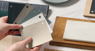A person holding paint samples above a design board.