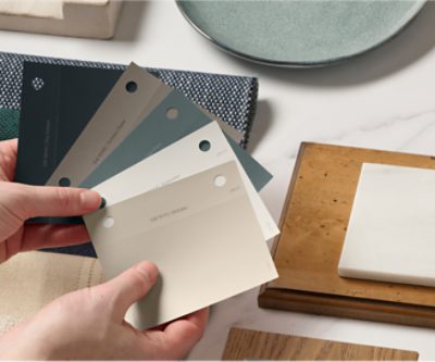 A person holding paint samples above a design board.