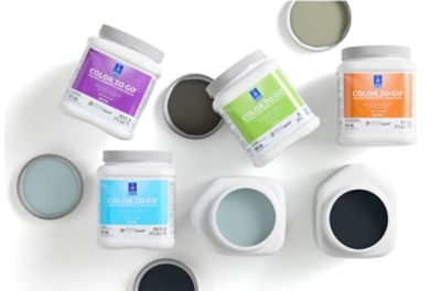 Multiple containers of Color to Go paint samples with some lids off to show the paint color inside.