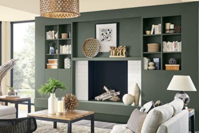 A living room with dark green built-in shelving around a white tiled fireplace.