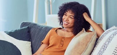 A smiling person sitting on a blue couch.