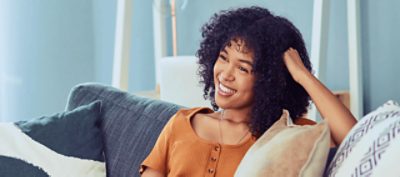 A smiling person sitting on a blue couch.
