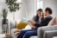 Two people sitting on a couch looking at a tablet together.