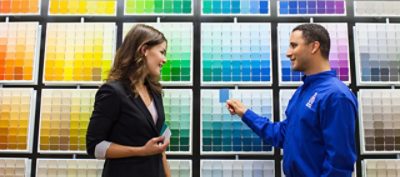 A Sherwin-Williams employee helping a customer choose a color in front of a color wall.