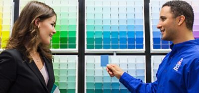 A Sherwin employee and a woman looking at paint color cards