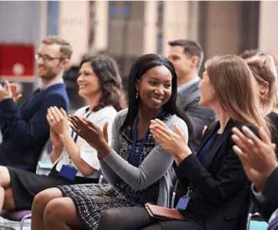 People clapping while sitting in an audience.