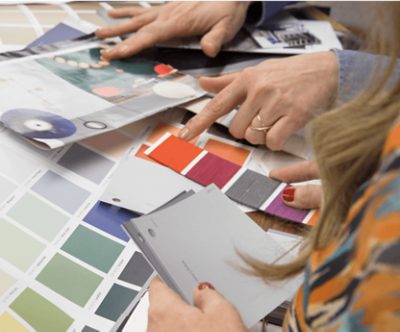 People looking at various color samples spread out on a table.