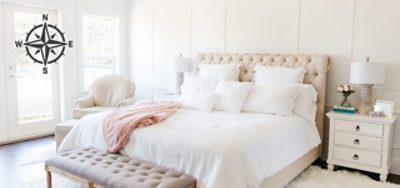 A bright bedroom with white walls and an upholstered bedframe.