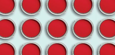 Tres filas que muestran muchas latas de pintura roja abiertas.