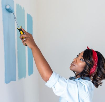 Person with a roller painting shades of blue on a wall.