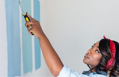 Person with a roller painting shades of blue on a wall.