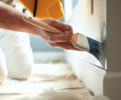 A person applying paint with a paint brush.