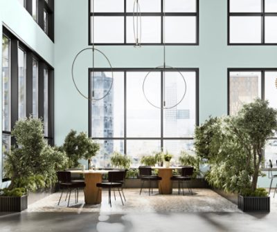 An atrium with tables and chairs among green plants with walls painted Tidewater SW6477.