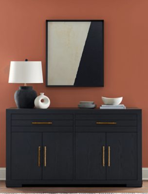 Wall painted in SW 2854 Caribbean Coral, with mirror hung and black dresser with lamp and dishware on top.