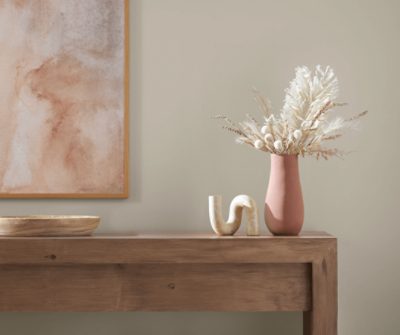 Neutral area with painting on wall with table of minimal decor on top.