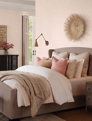 A bed with many throw pillows and a lumpy comforter.