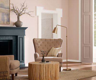 Living room with a circular coffee table, large chair next to a golden floor lamp and fireplace.