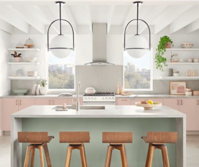 An open concept kitchen with a large waterfall island with lower cabinets painted Sashay Sand.