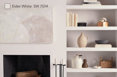 A recessed bookshelf next to a simple fireplace all painted Eider White SW 7014. 