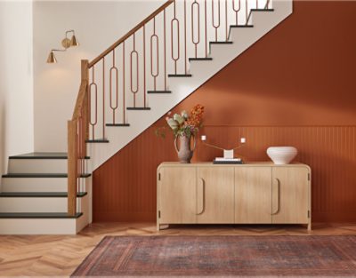Neutral staircase, wall below it is painted in SW 6349 Pennywise with wooden table and decor on top.