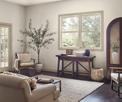 A living room with dark wood floors and a jute rug with walls painted Shoji White SW 7042.