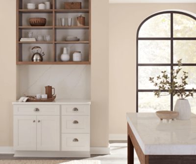 Kitchen walls painted in Sand Dollar SW 6099 with a coffee bar and open cabinet storage, island, and window.